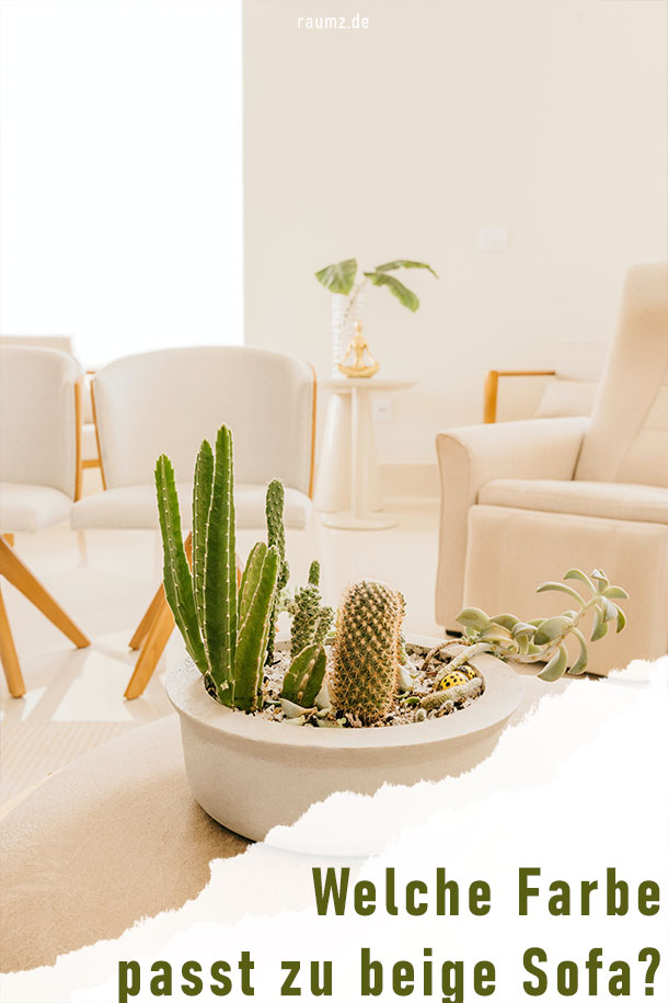 Einblick in ein Wohnzimmer mit beigefarbenen Sofas und Holzakzenten. Dekoriert wurde mit grünen Pflanzen. Am unteren Ende befindet sich ein Riss auf dem der Titel zu sehen ist: Welche Farbe passt zu beige Sofa?
