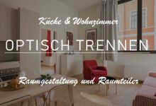 Titelbild mit der folgenden Aufschrift: "Küche und Wohnzimmer optisch trennen -Raumgestaltung und Raumteiler-. Auf dem Bild lässt sich eine Wohnküche erkennen, welche durch die Farbe der Möbel getrennt wird. Die Küche ist in neutralen Farben gehalten, während der Wohnbereich sich mit kräftigem Rot abhebt. Beispielsweise sind Sessel und Vorhänge in einem tiefen Rot gehalten.